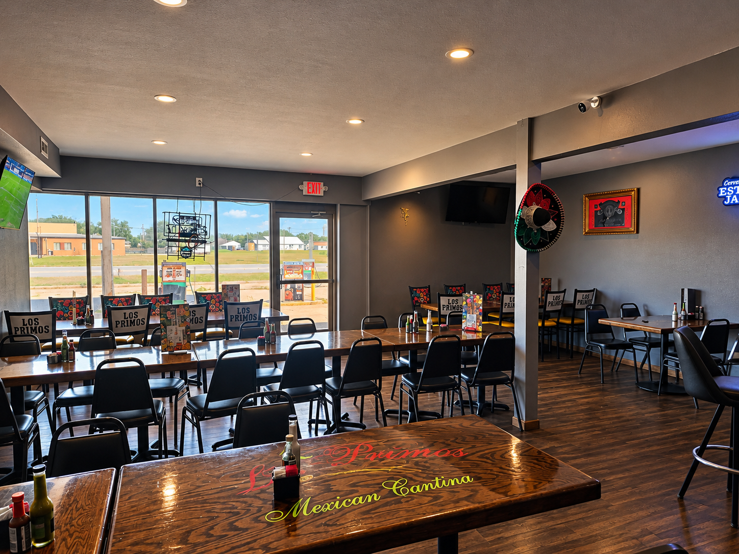 Dining area with Los Primos table signage and view toward the highway